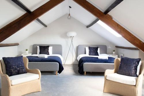 a attic bedroom with two beds and two chairs at Harbourside luxury house in Aberaeron