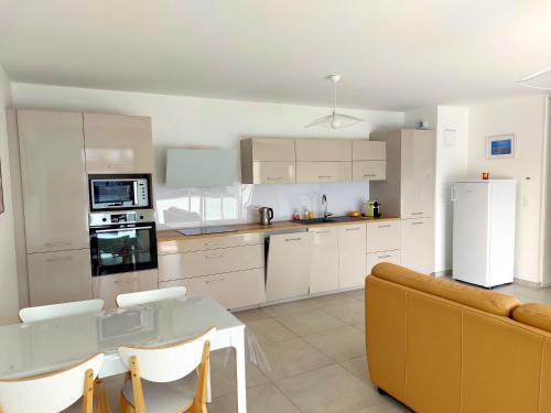 une cuisine avec des armoires blanches, une table et un canapé dans l'établissement Plein Soleil, à Aix-les-Bains