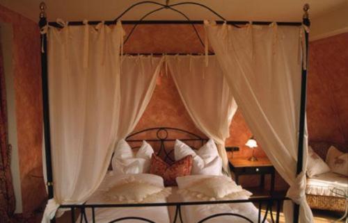 a canopy bed with white curtains in a bedroom at Hotel Bergwirt in Herrieden