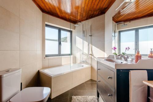 a bathroom with a tub and a sink and a toilet at Blue Lake House in Ferreira do Zêzere