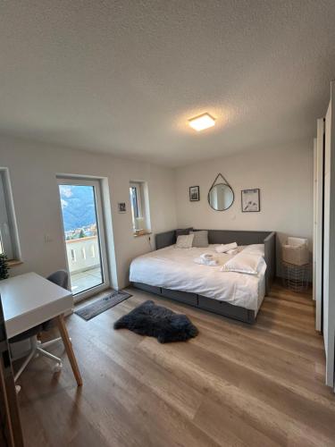 a bedroom with a bed and a desk and a window at 4 valleys Modern apartment with free parking in Nendaz