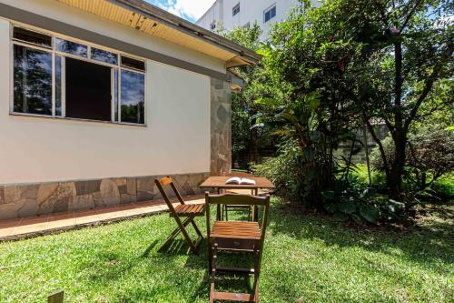 a table and chair in the yard of a house at Memora Guesthouse Curitiba - Quartos em Casa próximo ao Parque Bacacheri in Curitiba