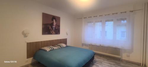 une chambre avec un lit bleu et une fenêtre dans l'établissement Strasbourg Centre Historique 15 mn en Tram et Aéroport Parking gratuit, à Lingolsheim