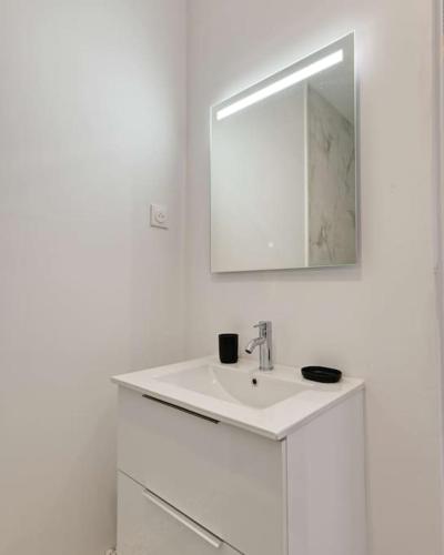 une salle de bain blanche avec un lavabo et un miroir dans l'établissement Sublime Appartement 3 chambres, à Marseille