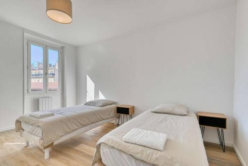 deux lits dans une chambre blanche avec une fenêtre dans l'établissement Sublime Appartement 3 chambres, à Marseille