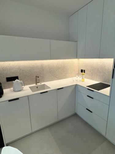 una cucina con mobili bianchi e un lavandino di Apartament Baltic Zefir Pogorzelica Sea&Spa-Hevenia a Pogorzelica