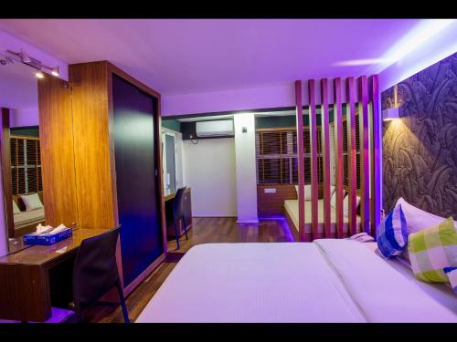 a bedroom with a bed and a desk with a computer at Ripple Beach Inn in Hulhumale