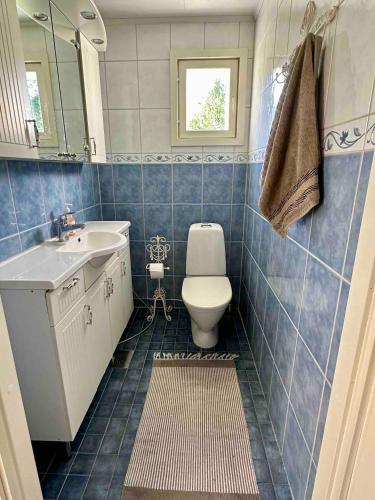 a blue tiled bathroom with a toilet and a sink at Villa Kesälä in Ylöjärvi