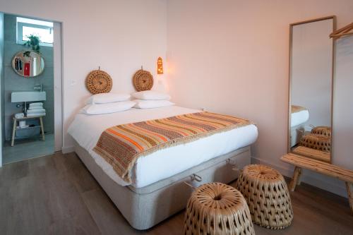 a bedroom with a bed with two ottomans at Casa do Rio in Nazaré