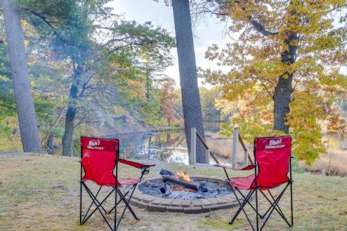 two red chairs sitting next to a fire pit at Antiquing and Fishing Riverfront Waupaca Home! in Waupaca