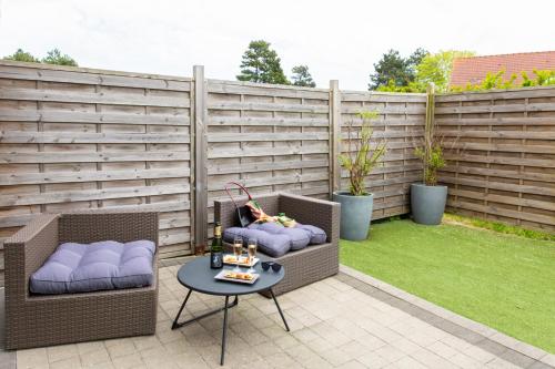 a patio with two chairs and a table and a fence at s'évader entre terre et mer in Gravelines