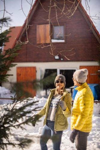 two people walking in the snow in front of a house at Villa Teodora in Kopaonik