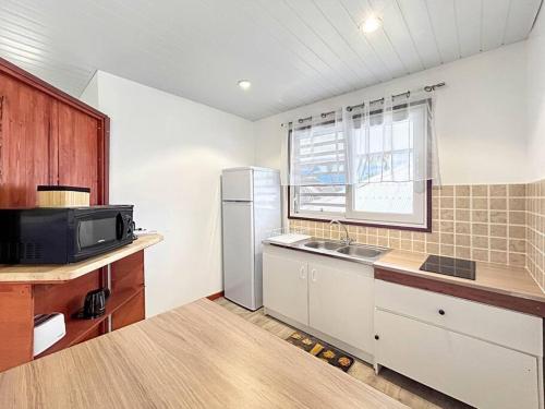 a kitchen with a refrigerator and a sink and a window at Free canoës King Bed - Fare Vaihere in Moorea