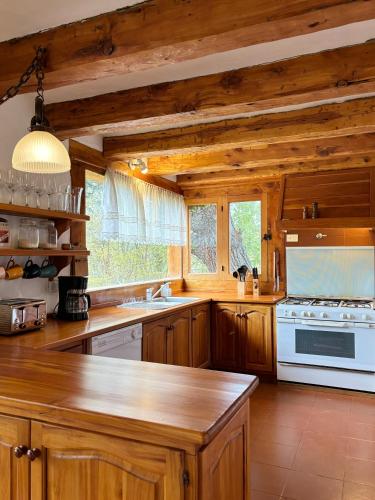 a kitchen with wooden cabinets and a white stove top oven at CASA de MONTAÑA CON VISTA AL LAGO in San Carlos de Bariloche