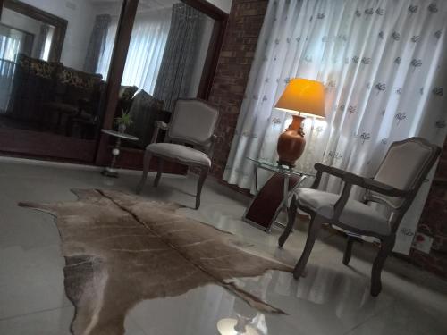 a living room with two chairs and a table with a lamp at 83 Ocean View in Port Shepstone