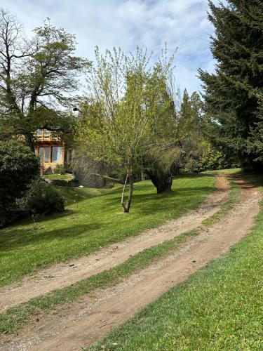a dirt road in a yard with trees and a house at CASA de MONTAÑA CON VISTA AL LAGO in San Carlos de Bariloche