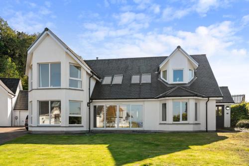 a white house with a black roof at Stunning Sea Views - Luxury 4BR Beach House in Oban