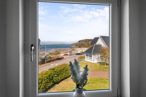 a window with a vase with flowers in front of it at Stunning Sea Views - Luxury 4BR Beach House in Oban