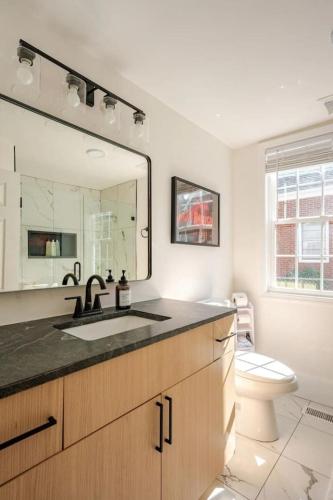a bathroom with a sink and a toilet and a mirror at Downtown Greenway Getaway in Raleigh