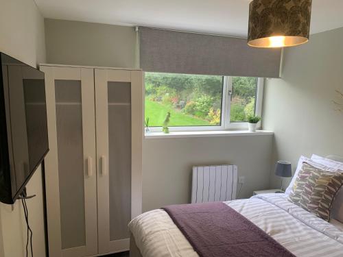 a bedroom with a bed and a window at Bronte Country - 2 Bed Apartment near Cliffe Castle in Keighley