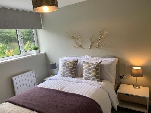 a bedroom with a bed with white sheets and pillows at Bronte Country - 2 Bed Apartment near Cliffe Castle in Keighley