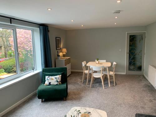 a living room with a table and a green chair at Bronte Country - 2 Bed Apartment near Cliffe Castle in Keighley