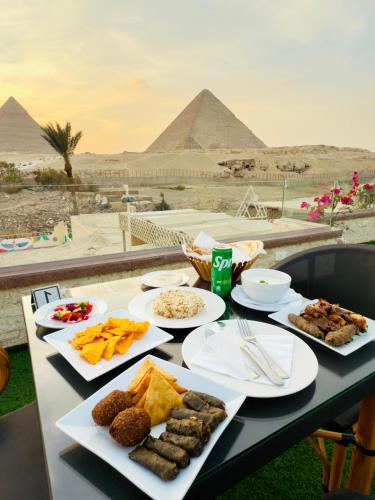 カイロにあるSeven Pyramids View Innのピラミッドを背景に盛り付けられたテーブル