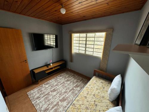 een kleine kamer met een bed en een televisie bij Chale Floresta in Campos do Jordão
