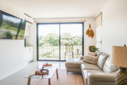 a living room with a couch and a large window at Mistico Serenity Shores at Nautilus in Playa Hermosa