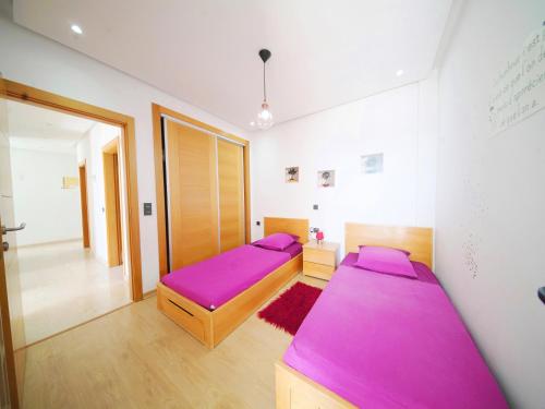 a bedroom with two beds with purple sheets at Geronticus apartment in Agadir