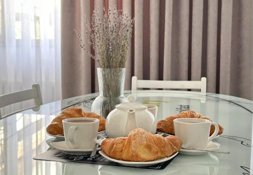 Una mesa de cristal con croissants y tazas de té encima. en Room& Breakfast Martin's Luxury Bologna, en Bolonia