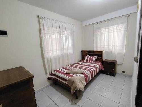 a bedroom with a bed with a red and white striped blanket at Villa Serenidad in Cochabamba