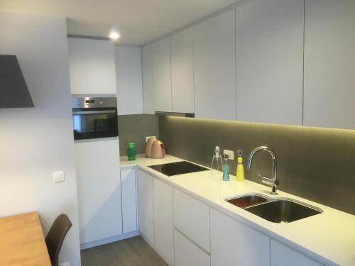 eine Küche mit weißen Schränken und einem Waschbecken in der Unterkunft Studio Appartement Van Bunnenplein in Knokke-Heist