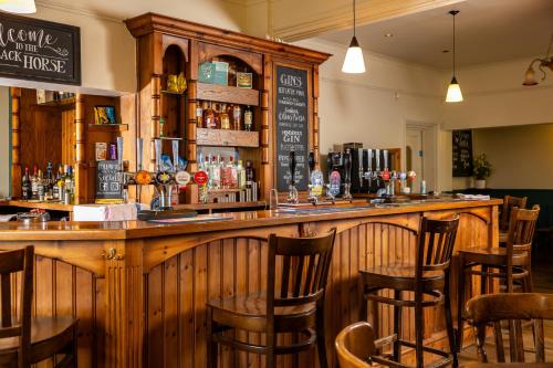 a bar in a restaurant with wooden chairs at The Black Horse in Swaffham Bulbeck