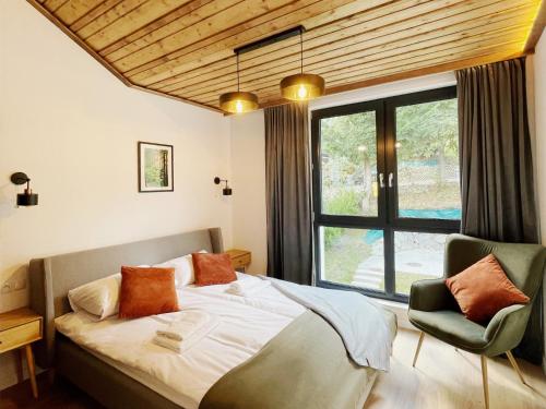 een slaapkamer met een bed, een raam en een stoel bij OWysoko - Apartamenty z Widokiem 200 m od tras Szczyrk Mountain Resort in Szczyrk