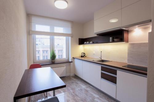 cocina con armarios blancos, mesa y ventana en Apartamenty Zamenhofa, en Białystok