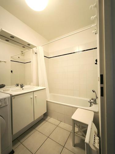 une salle de bain blanche avec un lavabo et une baignoire dans l'établissement Mon nid soulacais - Parking Privée, à Soulac-sur-Mer