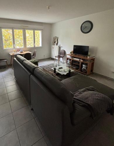 a living room with a couch and a clock on the wall at RnG-M in Échirolles