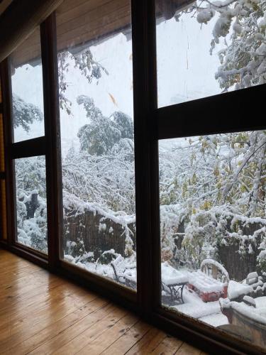 a window with a view of a snow covered yard at Cabañas Alegria Cajón del Maipo in San José de Maipo