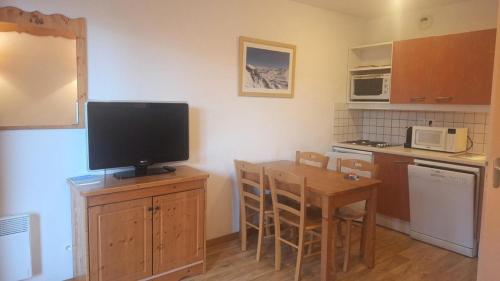 une cuisine avec une télévision au-dessus d'une table en bois dans l'établissement Résidence Hameau Des Ecrins - HEA405 - APPARTEMENT 1 CHAMBRE MAE-1811, à Narreyroux