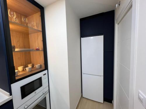 a small kitchen with a white refrigerator and cabinets at Apartment Arevalo 2B Parking Gratis in Lucena