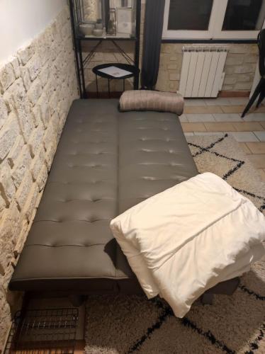 - un lit dans une pièce à côté d'un mur en pierre dans l'établissement Studio avec chambre Camargue, à Arles