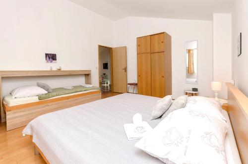 une chambre avec un grand lit avec des draps blancs dans l'établissement Apartments Sunny Corner, à Tribunj