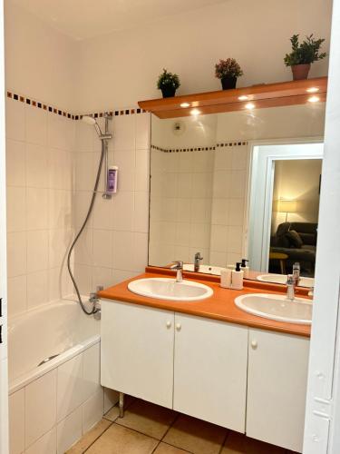 une salle de bain avec deux lavabos, un miroir et une baignoire dans l'établissement Appartement 2 pièces Paris près du Canal St-Martin, à Paris