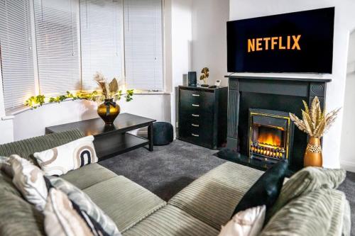 a living room with a couch and a television and a fireplace at The Cave in Coventry