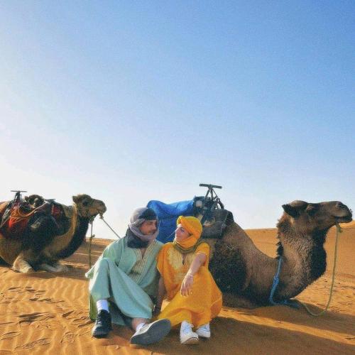 two women sitting on a camel in the desert at Merzouga Horizon Luxury Camp in Merzouga