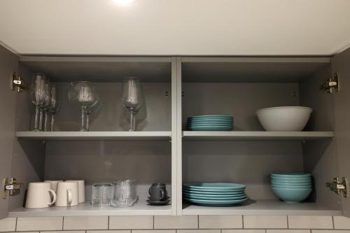 a cupboard with plates and glasses and dishes on it at Stylish 1 Bed Apartment in Bicester Town Centre in Bicester