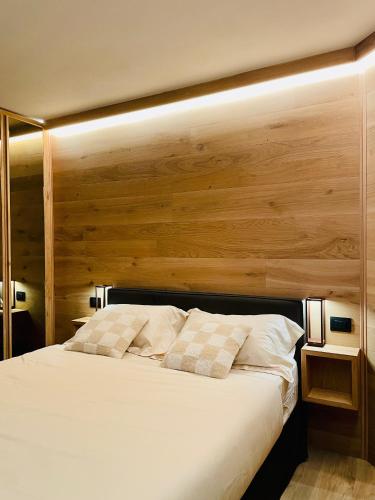 a bedroom with a white bed with a wooden wall at Panoramic Apartment in Breuil-Cervinia