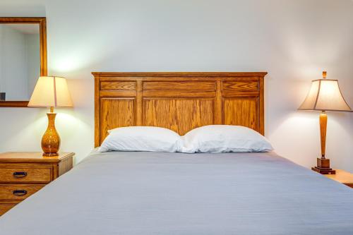 a bedroom with a bed with a wooden headboard and two lamps at Lakefront Home with Fire Pit in Eagle River in Eagle River