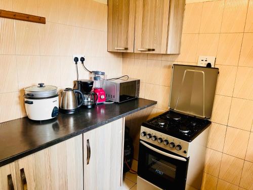 a kitchen with a stove and a microwave at Prime Two Bedroom Apartment, Kampala in Kampala